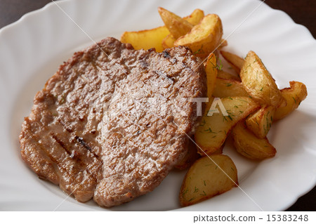Delicious pork chop and potato wedges, close-up 15383248