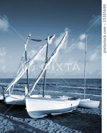 Small white sailing boats lay on the sandy beach Small white sailing boats lay on the sandy beach 15385699
