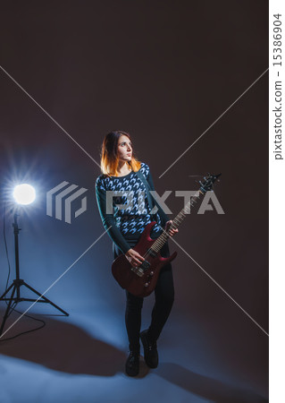 European appearance haired girl in a blue sweater playing a guit European appearance haired girl in a blue sweater playing a guit 15386904