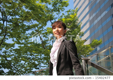 A woman standing in the city's fresh green 15402477