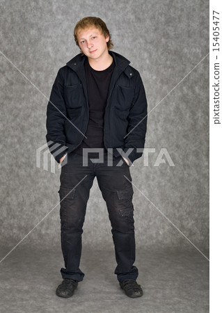Young guy in a jacket standing on a grey background 15405477