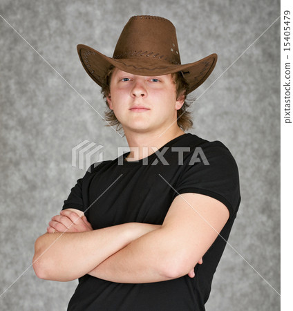 Beautiful serious young man in cowboy hat on grey background Beautiful serious young man in cowboy hat on grey background 15405479