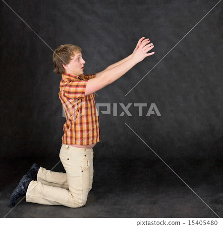 Amusing young man is kneeling and stretch hands to something Amusing young man is kneeling and stretch hands to something 15405480