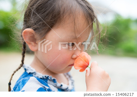 A girl sniffing the scent of a flower 15406217
