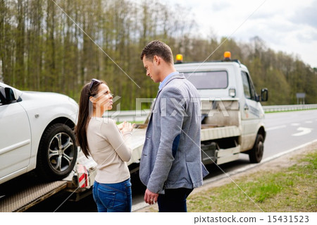 Couple near tow-truck picking up broken car 15431523