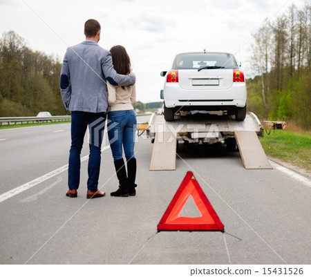 Couple near tow-truck picking up broken car 15431526