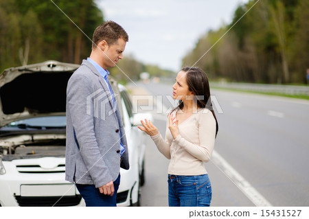 Couple near broken car on a highway roadside 15431527