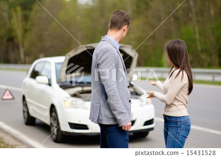 Couple near broken car on a highway roadside 15431528