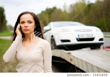 Woman calling while tow truck picking up her car 15431659