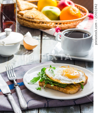 crispy toast with a fried egg and green arugula 15431942