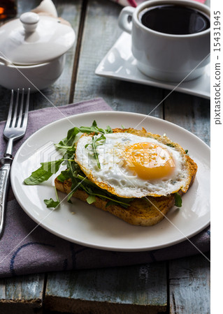 crispy toast with a fried egg and green arugula 15431945