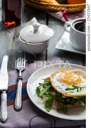 crispy toast with a fried egg and green arugula 15431947