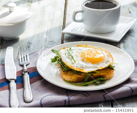 crispy toast with a fried egg and green arugula 15431951