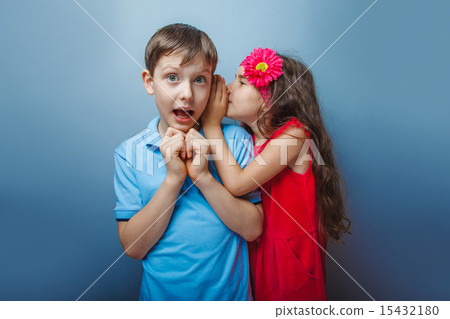 Teenage girl whispering in the ear of a secret teen boys on a g Teenage girl whispering in the ear of a secret teen boys on a g 15432180