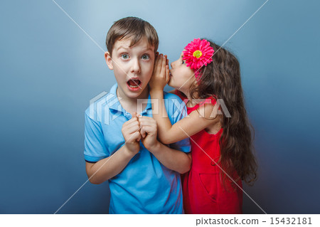 Teenage girl whispering in the ear of a secret teen boys on a Teenage girl whispering in the ear of a secret teen boys on a 15432181