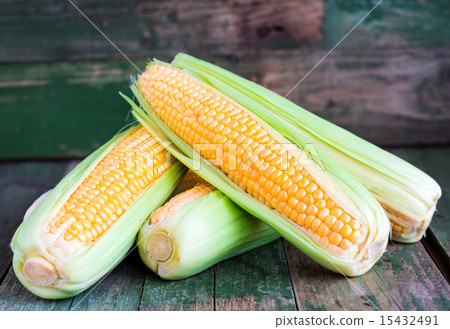 圖庫照片: raw corn on the cob on a green wooden background