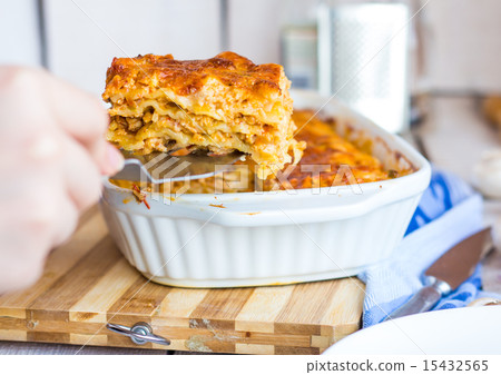 fed meat lasagna on a white plate, hand fed meat lasagna on a white plate, hand 15432565