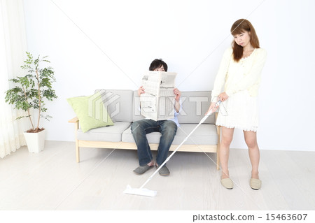 A woman cleaning and a man reading a newspaper A woman cleaning and a man reading a newspaper 15463607