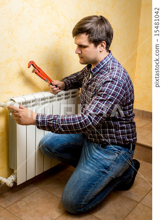 handyman fixing heating radiator with red plumber pliers handyman fixing heating radiator with red plumber pliers 15481042