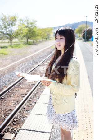 A young woman waiting for a train at the unmanned station in the country 15482328