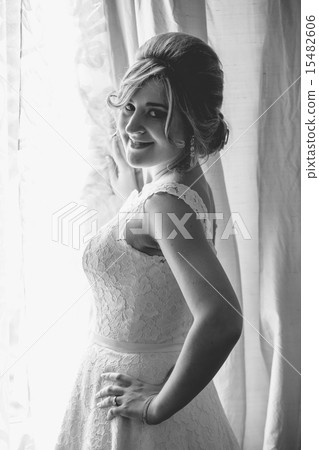 portrait of young bride posing at window in hotel 15482606
