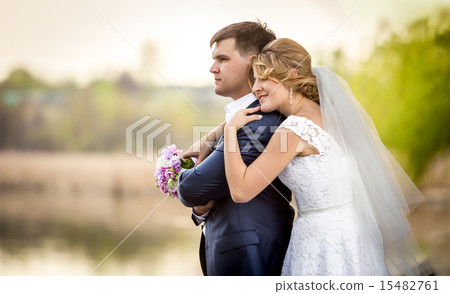 happy bride and groom hugging and looking at lake happy bride and groom hugging and looking at lake 15482761