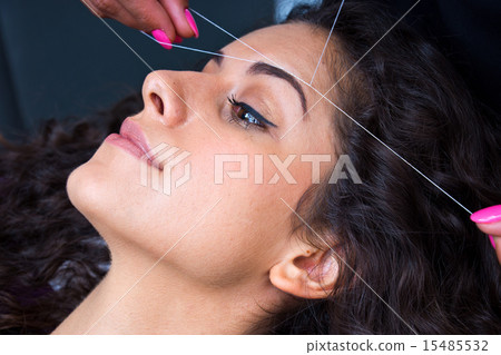 woman on facial hair removal threading procedure 15485532