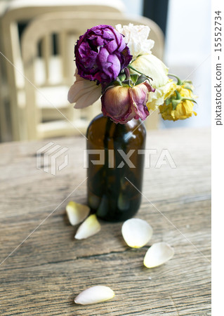Wither roses in bottle on wooden table 15552734