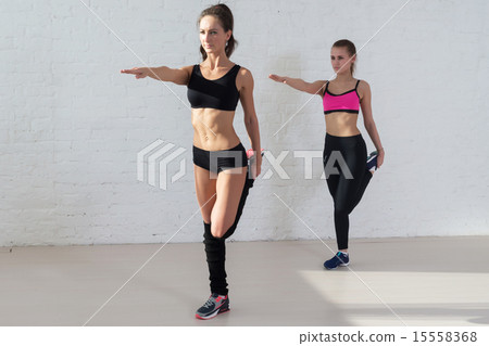 women doing stretching exercises warm up standing on one leg outstretched arm in front of her 15558368