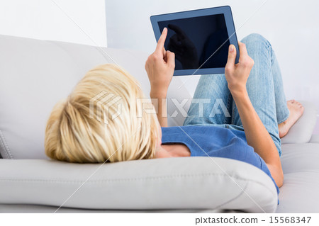 Blonde woman using her tablet on the couch Blonde woman using her tablet on the couch 15568347