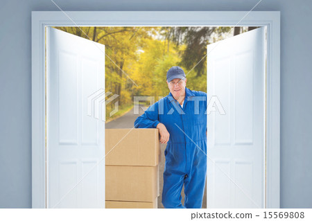 Composite image of happy delivery man leaning on pile of cardboa 15569808