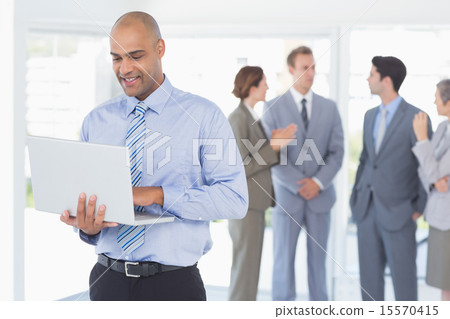 Businessman with his laptop and his colleagues behind Businessman with his laptop and his colleagues behind 15570415
