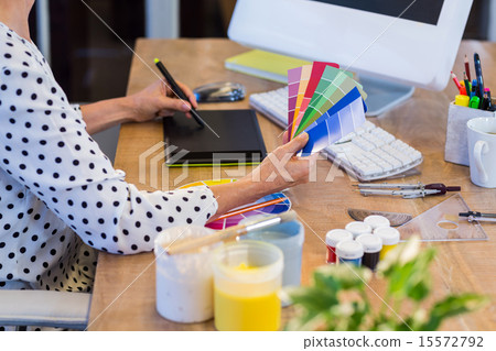 Casual businesswoman looking at colour swatch and drawing with d Casual businesswoman looking at colour swatch and drawing with d 15572792