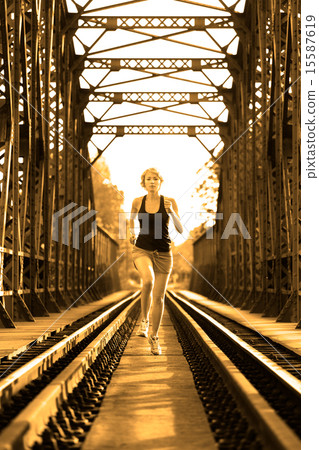 Active female athlete running on railaway tracks. 15587619