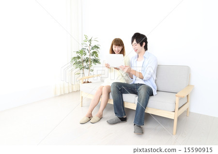 A couple looking at a computer in the living room 15590915