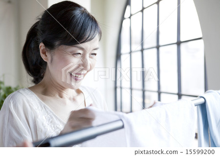 Female in her 50s hanging up laundry 15599200