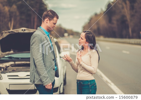 Couple near broken car on a highway roadside 15600879
