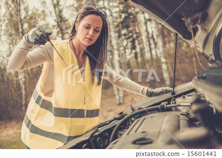 Woman checking oil level on a roadside Woman checking oil level on a roadside 15601441
