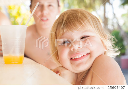 Smiling cute blond Caucasian baby girl with juice 15605407