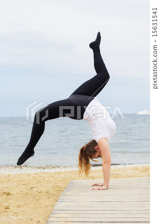 Sportive plump woman doing hatha yoga near the sea 15631541