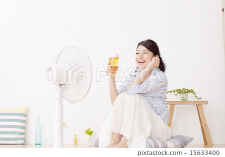 一個女人喝啤酒，同時擊中一個風扇 15633400