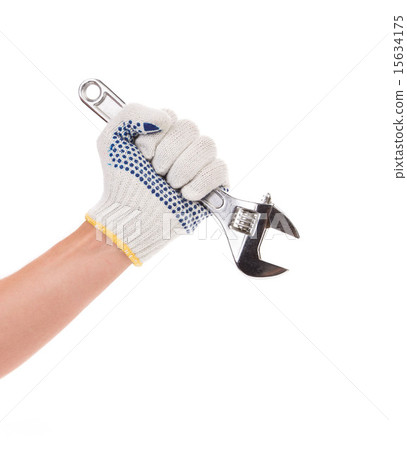 Hand in gloves holding adjustable wrench. 15634175