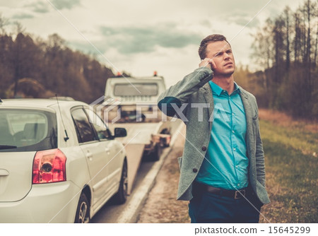 Man calling while tow truck picking up his broken car 15645299