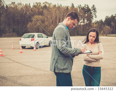 Driving instructor and woman student in examination area 15645322