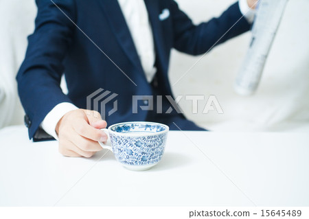 A man watching a newspaper holding a coffee cup A man watching a newspaper holding a coffee cup 15645489