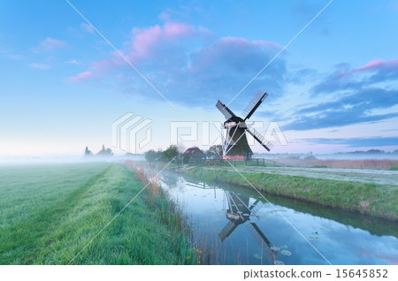 Dutch windmill by river at sunrise 15645852
