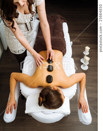 Massage therapist applying a hot stone massage 15664850