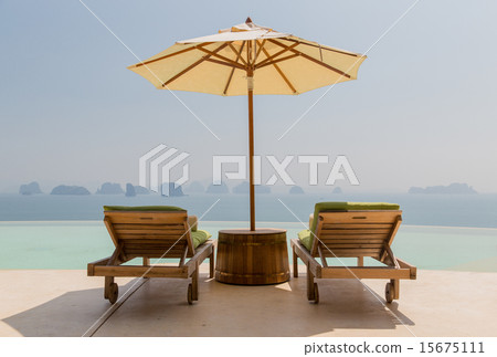 infinity pool with parasol and sun beds at seaside 15675111