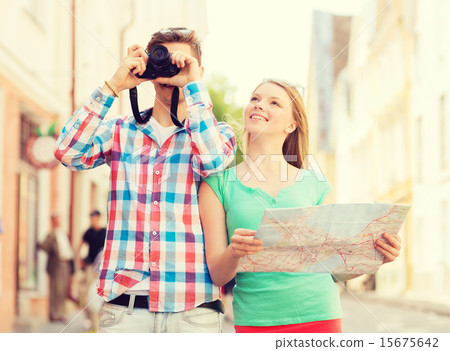smiling couple with map and photo camera in city 15675642