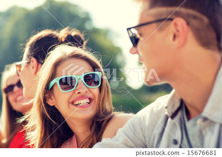 group of smiling friends sitting on city street 15676681